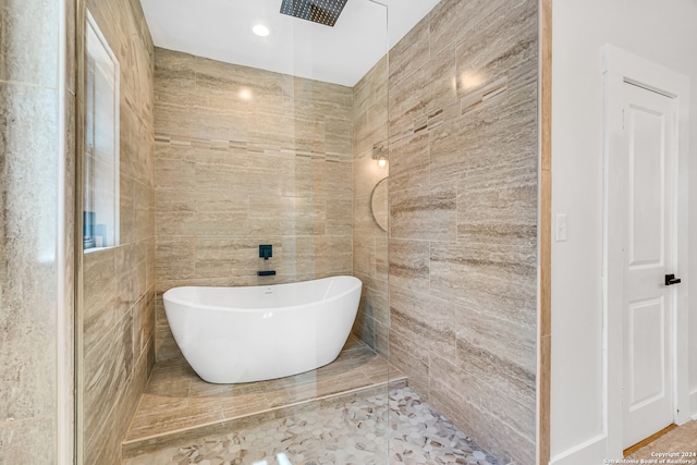 bathroom featuring shower with separate bathtub, tile walls, and tile patterned floors