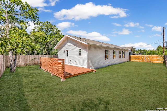 back of house featuring a lawn and a deck