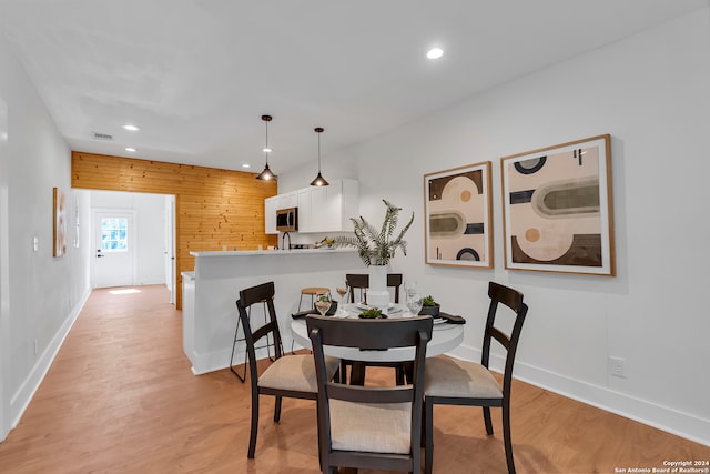 dining room featuring light wood-type flooring and wood walls