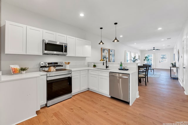 kitchen featuring pendant lighting, light wood-type flooring, sink, kitchen peninsula, and appliances with stainless steel finishes