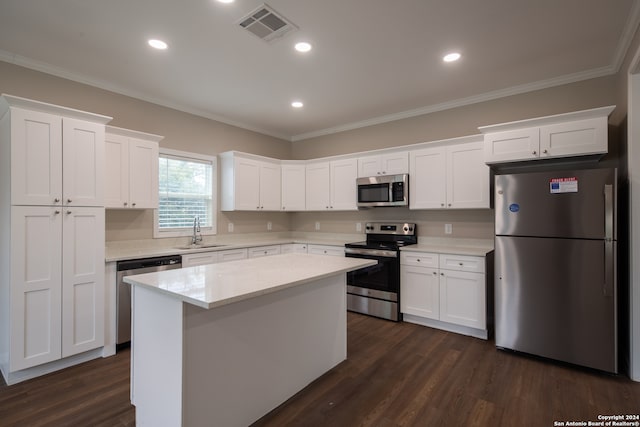 kitchen with appliances with stainless steel finishes, a kitchen island, dark hardwood / wood-style flooring, and white cabinets