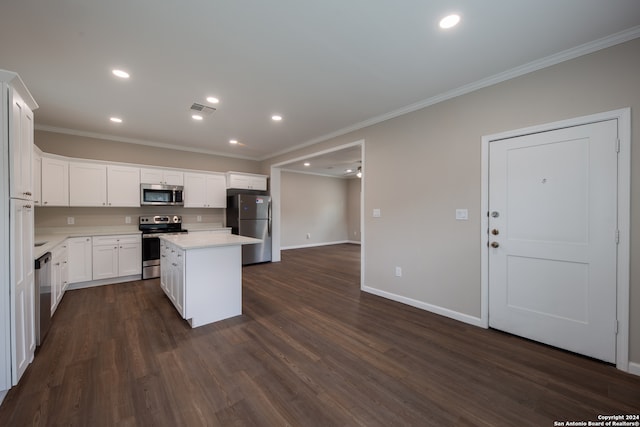 kitchen with appliances with stainless steel finishes, white cabinetry, a kitchen island, ornamental molding, and dark hardwood / wood-style floors