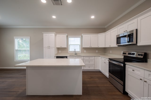 kitchen with appliances with stainless steel finishes, white cabinets, a kitchen island, and plenty of natural light