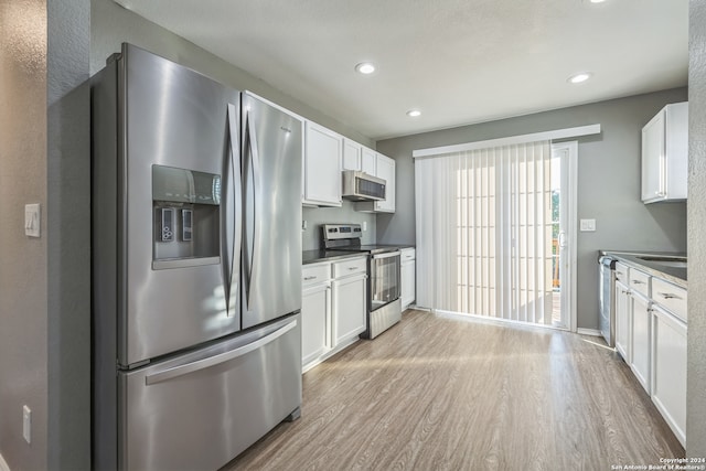 kitchen featuring appliances with stainless steel finishes, light hardwood / wood-style floors, and white cabinetry