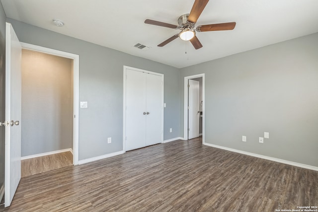 unfurnished bedroom featuring ceiling fan, a closet, and dark wood-type flooring