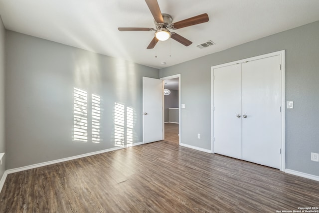 unfurnished bedroom with a closet, ceiling fan, and dark wood-type flooring