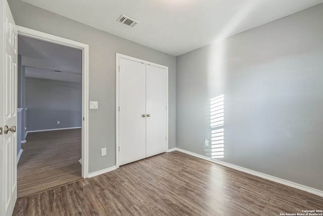 unfurnished bedroom with a closet and dark hardwood / wood-style flooring