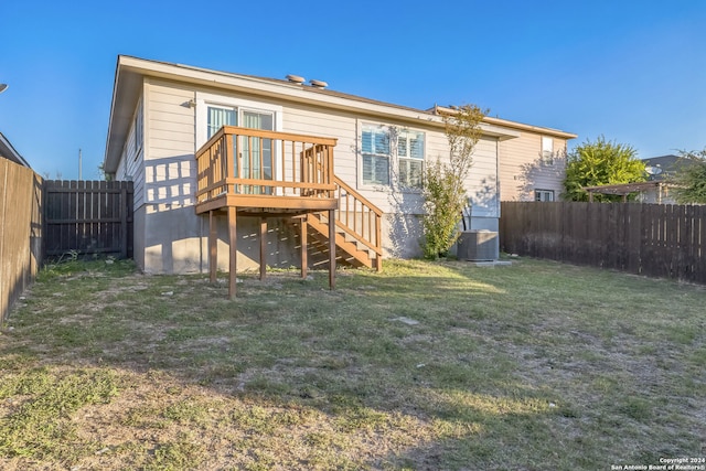 back of property featuring a wooden deck, a yard, and central AC