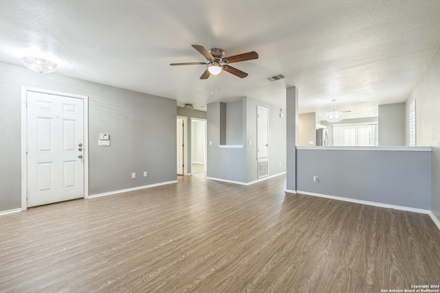 unfurnished living room with a textured ceiling, wood-type flooring, and ceiling fan