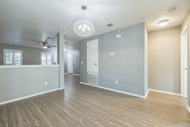 unfurnished room featuring ceiling fan with notable chandelier and wood-type flooring