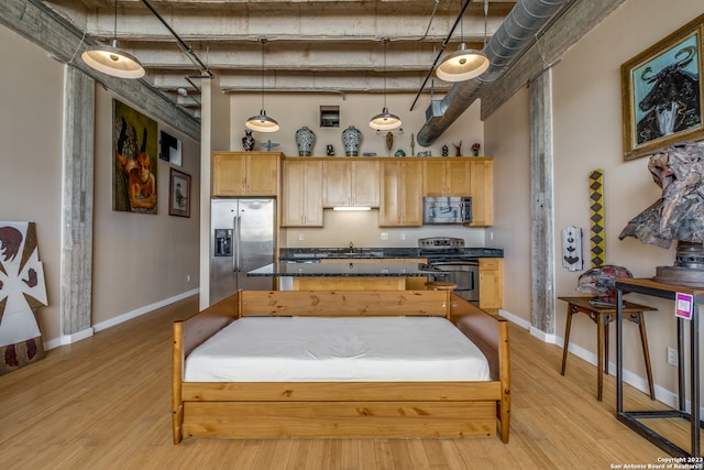 kitchen with appliances with stainless steel finishes, light hardwood / wood-style floors, light brown cabinetry, and pendant lighting