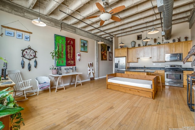 1331 S Flores St Unit 213, San Antonio, TX 78204 - kitchen with light wood finished floors, stainless steel appliances, dark countertops, a ceiling fan, and hanging light fixtures
