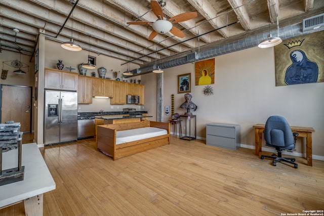 kitchen featuring light wood-type flooring, ceiling fan, stainless steel appliances, and decorative light fixtures