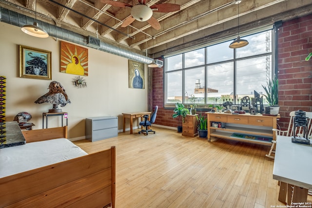 miscellaneous room featuring hardwood / wood-style floors, ceiling fan, and brick wall