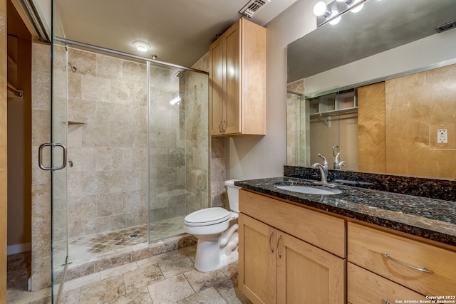 bathroom with a shower with shower door, vanity, and toilet