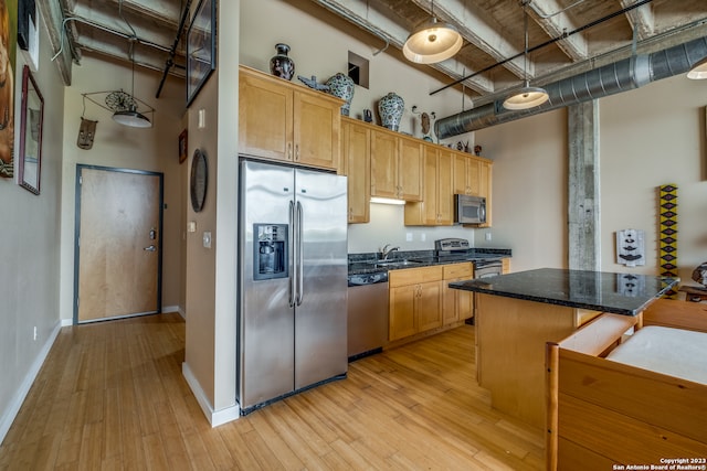 kitchen featuring light hardwood / wood-style floors, a towering ceiling, sink, and stainless steel appliances