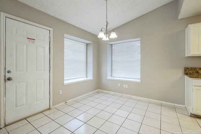 unfurnished dining area featuring a textured ceiling, light tile patterned flooring, vaulted ceiling, and a chandelier