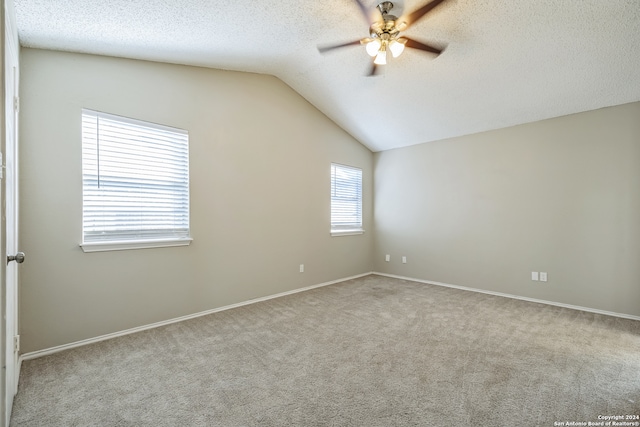 carpeted spare room with lofted ceiling, ceiling fan, and a textured ceiling