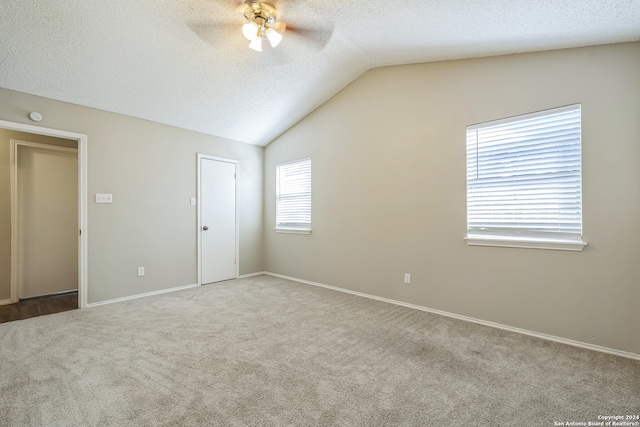 carpeted empty room with lofted ceiling, ceiling fan, and a textured ceiling