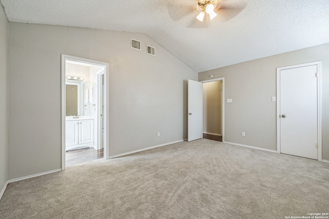 unfurnished bedroom with light carpet, connected bathroom, lofted ceiling, and ceiling fan