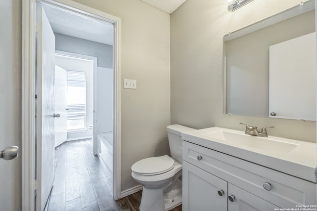 bathroom with a textured ceiling, hardwood / wood-style flooring, vanity, and toilet