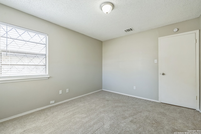 unfurnished room featuring a textured ceiling and light colored carpet