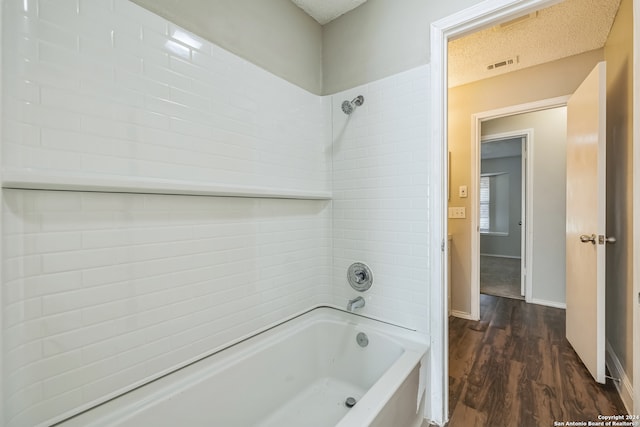 bathroom featuring a textured ceiling, tiled shower / bath combo, and wood-type flooring