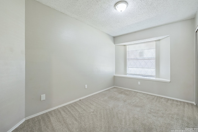 carpeted empty room with a textured ceiling