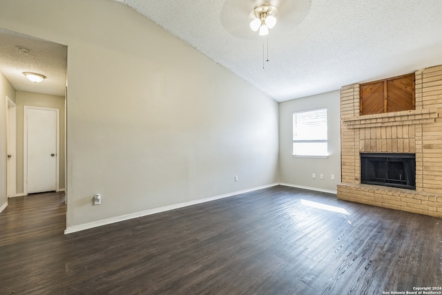 unfurnished living room featuring ceiling fan, lofted ceiling, a brick fireplace, a textured ceiling, and dark hardwood / wood-style floors