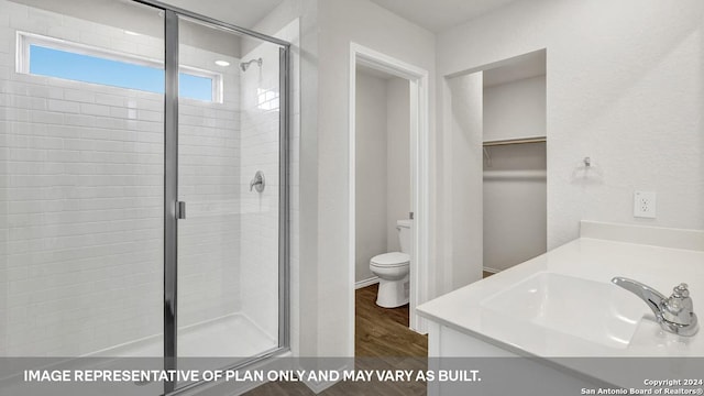 bathroom with wood finished floors, a stall shower, a spacious closet, vanity, and toilet