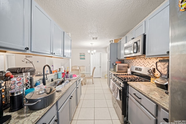 kitchen featuring pendant lighting, light tile patterned flooring, sink, a notable chandelier, and appliances with stainless steel finishes