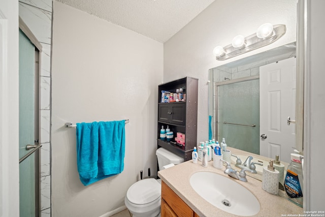 bathroom with vanity, a textured ceiling, a shower with shower door, and toilet