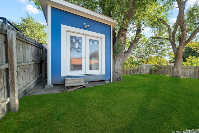 view of outdoor structure featuring a yard and french doors