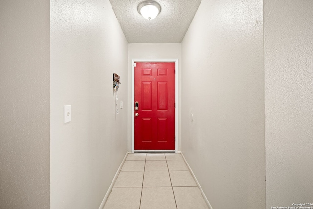 doorway to outside with a textured ceiling and light tile patterned flooring