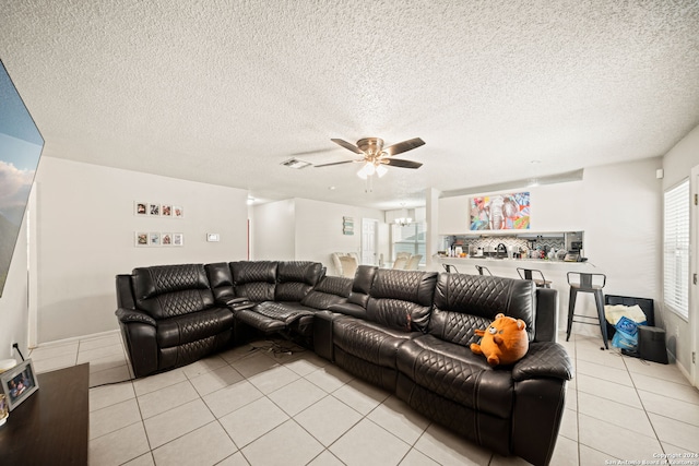 living room with ceiling fan, a textured ceiling, and light tile patterned floors