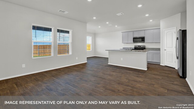 kitchen featuring an island with sink, dark hardwood / wood-style floors, stainless steel appliances, and light stone countertops