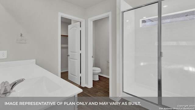 bathroom with hardwood / wood-style floors, a shower with door, toilet, and vanity