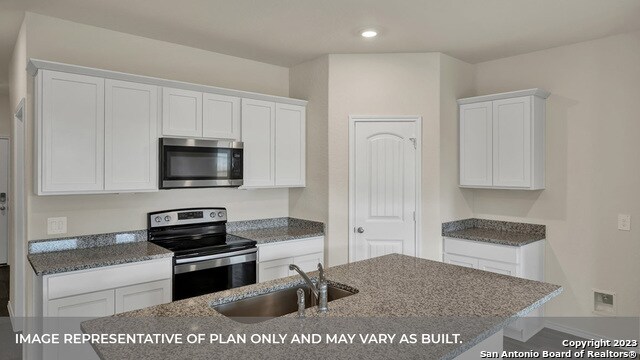 kitchen with white cabinetry, appliances with stainless steel finishes, a kitchen island with sink, and sink