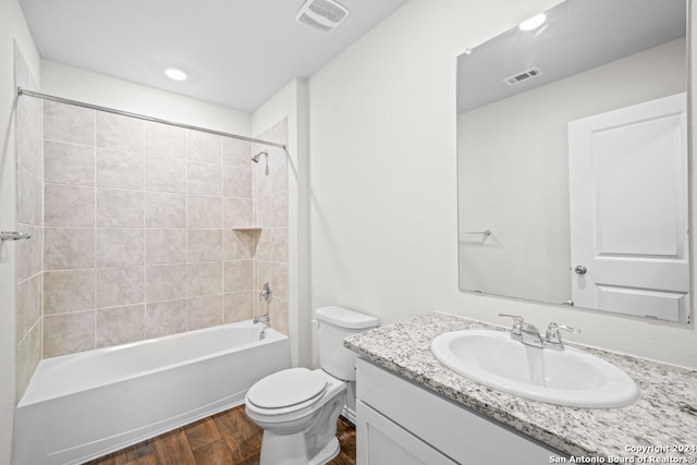 full bathroom featuring tiled shower / bath, vanity, hardwood / wood-style floors, and toilet