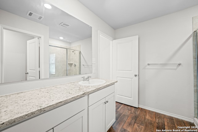 bathroom featuring hardwood / wood-style flooring, a shower with door, and vanity