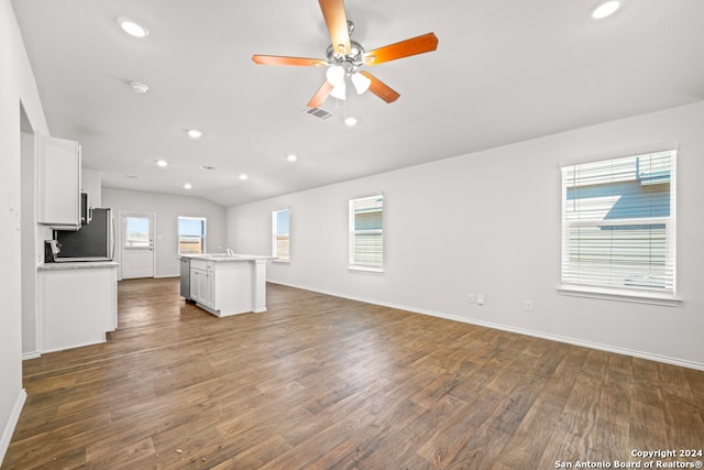 unfurnished living room featuring vaulted ceiling, dark hardwood / wood-style floors, ceiling fan, and plenty of natural light