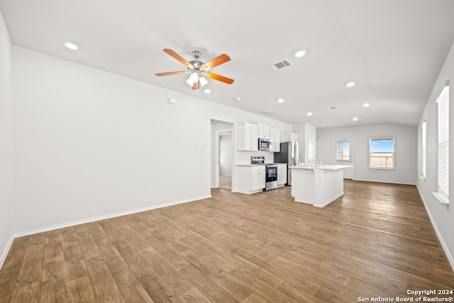 unfurnished living room with light wood-type flooring, vaulted ceiling, ceiling fan, and sink