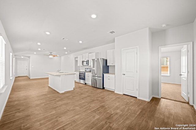 kitchen with ceiling fan, an island with sink, white cabinetry, stainless steel appliances, and light hardwood / wood-style floors