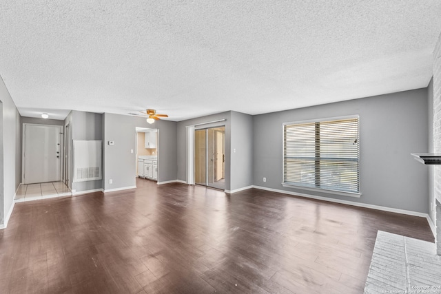 unfurnished living room with wood-type flooring, a textured ceiling, a fireplace, and ceiling fan