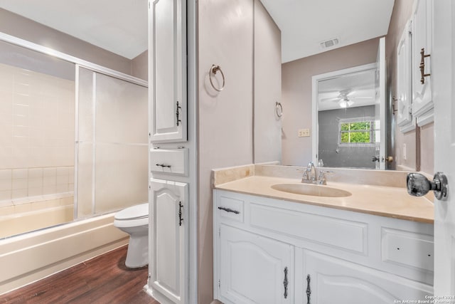 full bathroom featuring vanity, toilet, shower / bath combination with glass door, ceiling fan, and hardwood / wood-style floors