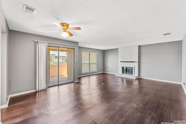 unfurnished living room featuring a textured ceiling, dark hardwood / wood-style flooring, and a brick fireplace