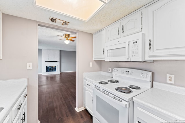 kitchen with white cabinets, white appliances, a textured ceiling, dark hardwood / wood-style floors, and a fireplace