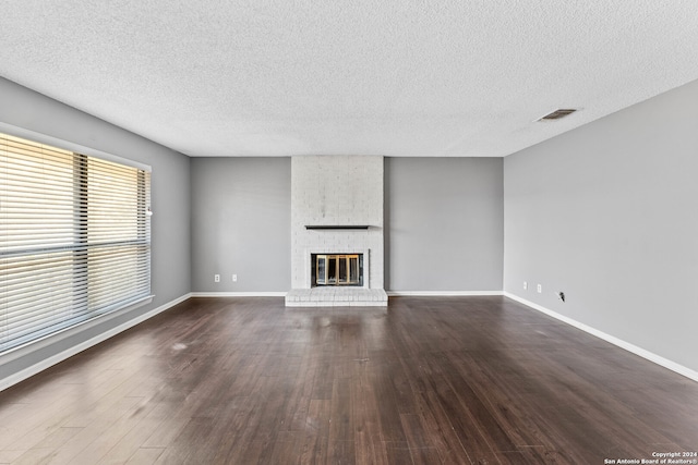 unfurnished living room with a textured ceiling, a fireplace, and dark hardwood / wood-style flooring