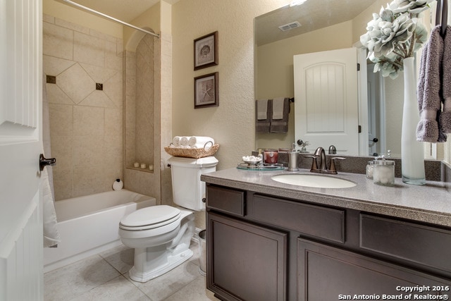 full bathroom with tile patterned floors, tiled shower / bath combo, vanity, and toilet