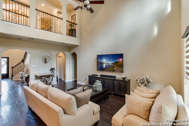 living room featuring a high ceiling, ceiling fan, and dark wood-type flooring